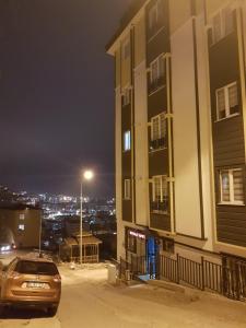 トラブゾンにあるNURALP APART OTEL - Trabzonの夜間の建物前に停車する車