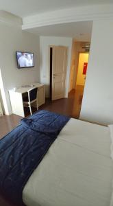 
a hotel room with a bed, television, and bedside table at Guest House Šterk in Nova Gorica
