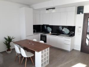 - une cuisine avec une table en bois et des placards blancs dans l'établissement Sophia Sunset Lakeview Mamaia Apartment, à Mamaia