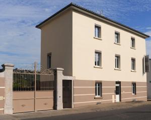 ein großes weißes Gebäude mit einem Tor in der Unterkunft Aux Jardins de L'Isle in Vienne