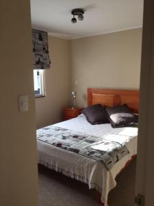 a bedroom with a bed with a wooden headboard and pillows at Casa Condominio Los Robles in Pucón