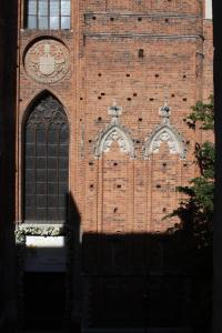 a brick building with two windows and a clock on it at Apartament Przy Katedrze in Toruń