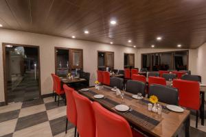 una habitación con una mesa larga y sillas rojas en Hotel Seven Oaks en Mussoorie