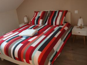 - un lit avec une couette rayée colorée dans l'établissement Cottage nuiton, à Nuits-Saint-Georges