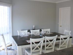 a dining room with a black table and white chairs at Numurkah Self Contained Apartments - The Saxton in Numurkah