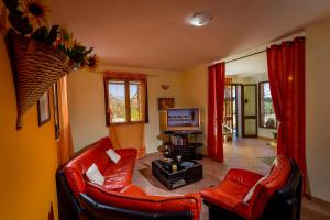 Sala de estar con 2 sillas de cuero rojo y TV en Villa Oasi del Relax, en Castellammare del Golfo
