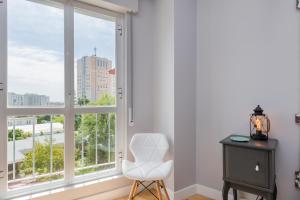une chaise blanche dans une chambre avec fenêtre dans l'établissement Lisbon Airport Hostel, à Lisbonne