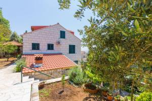 a white house with a red roof and a yard at Sobe na Konalu in Dubrovnik