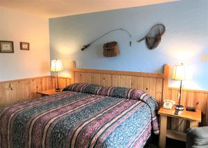 ミノクアにあるNorthwoods Inn & Suites Minocquaのベッドルーム1室(ベッド1台、ランプ付きテーブル2台付)