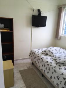 ein Schlafzimmer mit einem Bett und einem TV an der Wand in der Unterkunft Apartamento pé na areia in Itanhaém