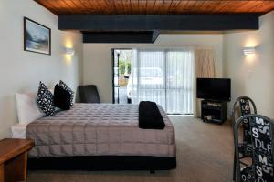 1 dormitorio con 1 cama grande y TV en Wylie Court Motor Lodge en Rotorua