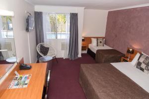 
a room with a bed, a chair, and a window at Hampton Villa Motel in Rockhampton
