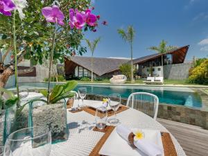 a table with wine glasses and flowers on a table in front of a pool at The Layar - Designer Villas and Spa, CHSE Certified in Seminyak
