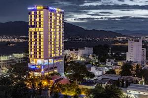 ein beleuchtetes Gebäude in einer Stadt in der Nacht in der Unterkunft Dendro Gold Hotel in Nha Trang