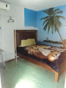 ein Schlafzimmer mit einem Bett mit einem Palmenmilch in der Unterkunft Cabinas Dormi Bene in Miramar