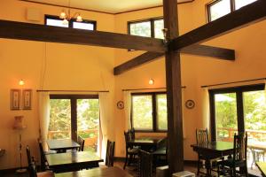 a dining room with tables and chairs and windows at Lumiere in Fujikawaguchiko