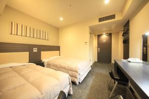 a hotel room with two beds and a desk at R&B Hotel Hachioji in Hachioji