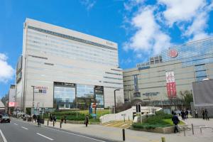 a large white building on a city street with people at Solaria Nishitetsu Hotel Fukuoka in Fukuoka