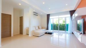 a living room with a couch and a television at Hideaway Pool Villa S126 in Suan Son