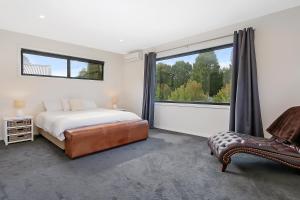 a bedroom with a bed and a chair and a large window at Divine - In the heart of Bright in Bright