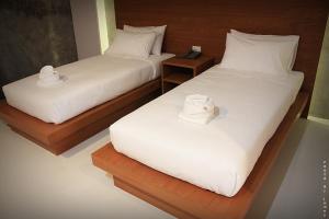 dos camas con sábanas blancas y sombreros. en Merdelong Hotel, en Phatthalung