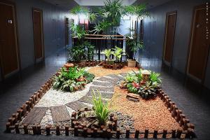 a garden in a building with plants and rocks at Merdelong Hotel in Phatthalung