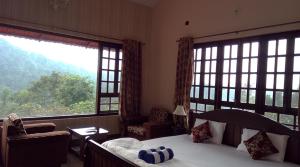 a bedroom with a bed and two large windows at Abiyal Mountain Stay in Madikeri