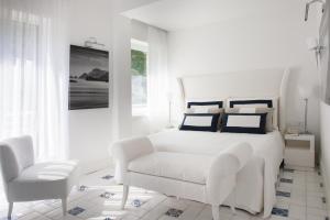 a white bedroom with a white bed and a chair at Jumeirah Capri Palace in Anacapri