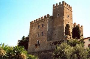 un gran castillo de ladrillo con árboles delante de él en Le Camere Di Paolino, en Manciano