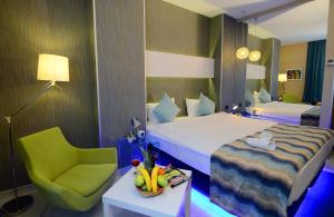 a hotel room with two beds and a green chair at Tempo Hotel 4Levent in Istanbul