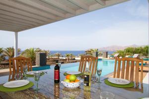 una mesa con botellas de vino y un bol de fruta junto a una piscina en Villa Luna Mar en Puerto Calero