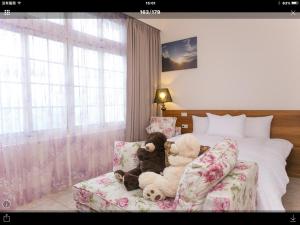 Dois ursinhos sentados num sofá num quarto em House of San Sia Ah Kuei em Sanxia