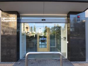 a bench in front of a building with a glass door at Lights Landing Apartments in Adelaide