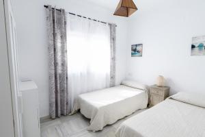 1 dormitorio blanco con 2 camas y ventana en Apartamento Pasaje Del Mar, en El Puerto de Santa María