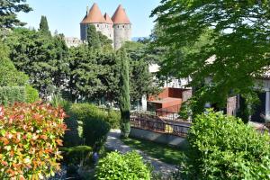 a castle in the middle of a garden with trees at Hotel Pont Levis - Franck Putelat in Carcassonne