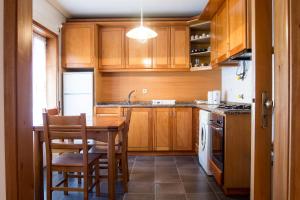 a kitchen with wooden cabinets and a table and chairs at Deluxe Apart in Furadouro