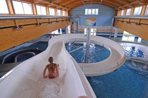 a person riding a water slide in a swimming pool at Apartman Lipno in Frymburk