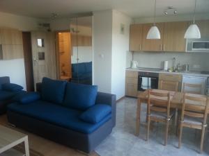 a living room with a blue couch and a table at Apartament Rega Mrzeżyno in Mrzeżyno