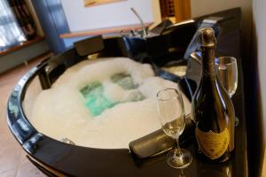 Ben Akiba Luxury Suites في بلغراد: حوض استحمام ساخن مع زجاجة من الشمبانيا وكأس