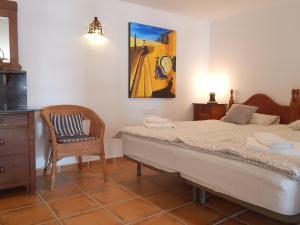 a bedroom with a bed and a chair and a painting at Apartment Burriana in Nerja