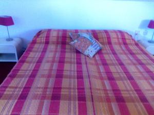 a bed with a plaid blanket with a pillow on it at Bed & Breakfast aan Zee in Callantsoog