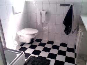 a bathroom with a toilet and a black and white checkered floor at Bed & Breakfast aan Zee in Callantsoog