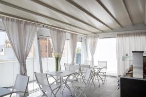 a dining room with white chairs and tables and windows at Palazzo Perla - Rooms and Suite in Gallipoli