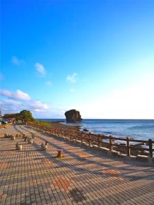 een rij banken op een strand naast het water bij Jing Guan Hotel in Eluan