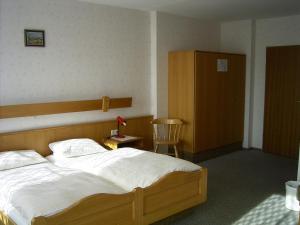 a bedroom with a large bed and a chair at Hotel Sonnenhof in Thannhausen