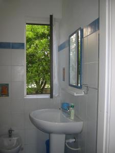 baño blanco con lavabo y ventana en La Via Del Mare en Arenella