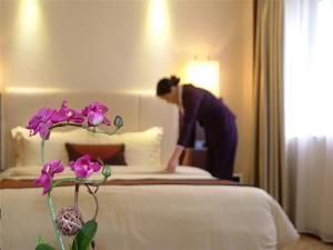 a woman bending over a bed in a hotel room at Guangdong Hotel in Guangzhou