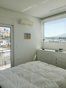 een witte slaapkamer met een groot bed en een raam bij Mind-blowing Acropolis View Apt in Athene