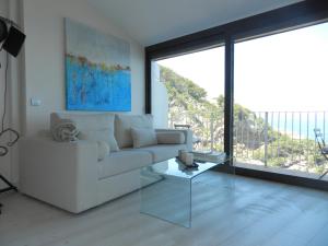 uma sala de estar com um sofá branco e uma mesa de vidro em Cap sa Sal Lofts em Begur