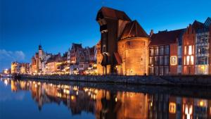 a city lit up at night next to a river at Apartamenty nad Motławą I in Gdańsk